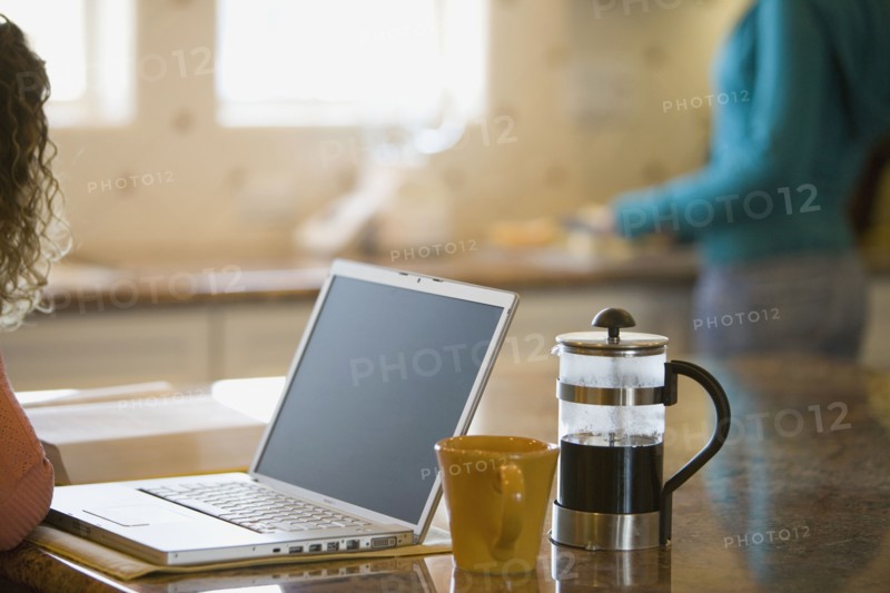 Young woman drinking coffee and working on her laptop in the morning