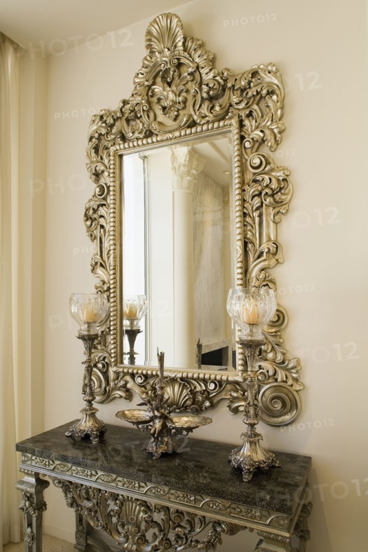 Detail of a decorative mirror above a small side table