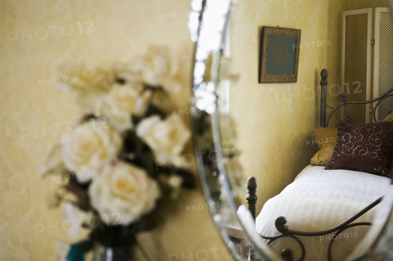 Detail of white roses next to antique vanity mirror.