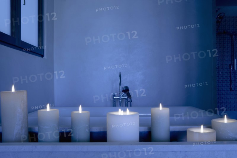 Night scene with a collection of lit candles in front of a bathtub
