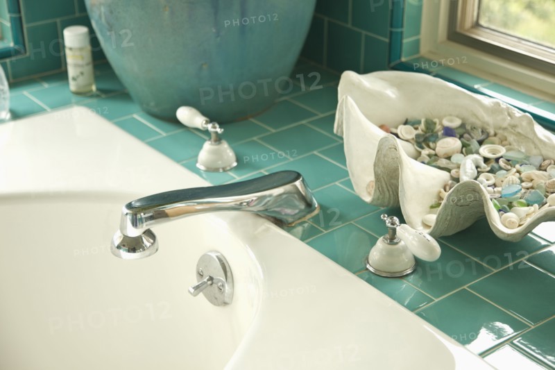 Decorative shells on aqua tile bathroom counter near sink