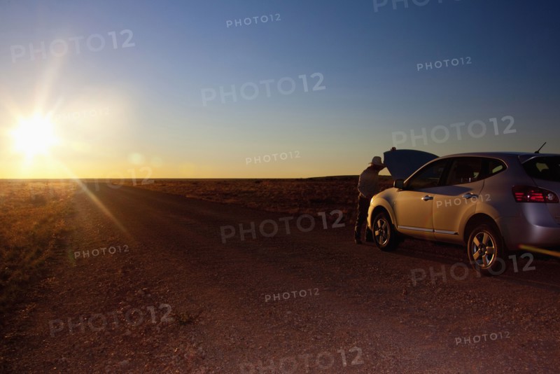 Person opening hood of car on remote road