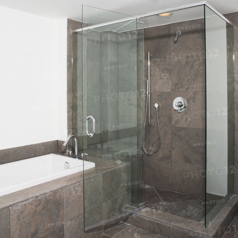 Glass doors of shower and bathtub in modern bathroom