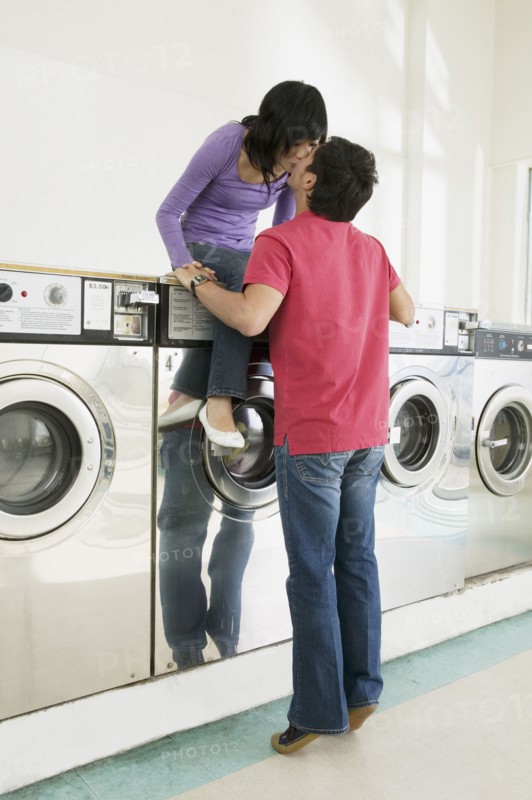 Asian couple kissing in laundromat
