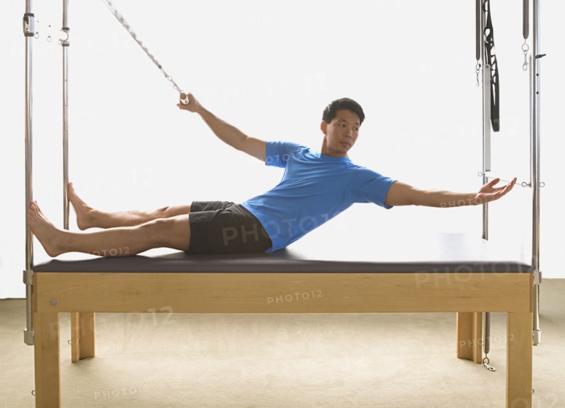 Asian man stretching on exercise equipment