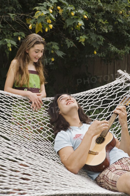 Pacific Islander man playing ukulele for sister