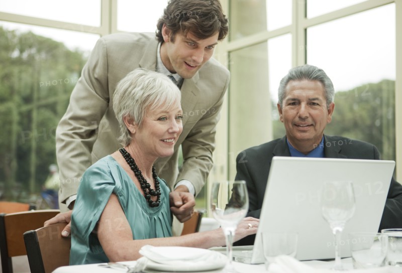 Business people using laptop at table in restaurant