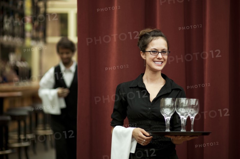 Smiling Hispanic waitress carrying tray of wine glasses