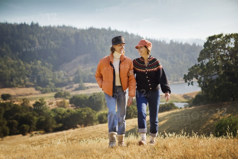 Women walking arm in arm near field