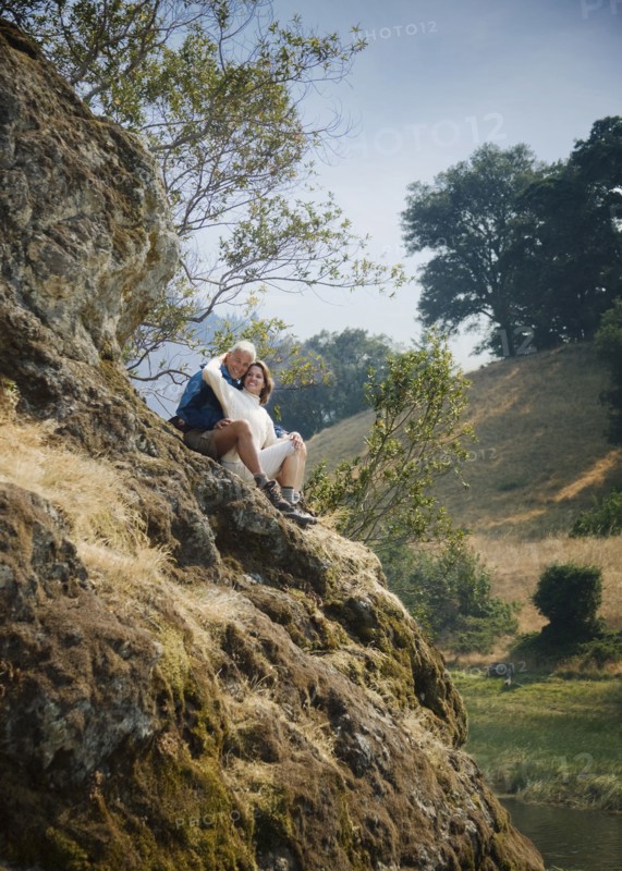 Caucasian couple sitting on hill near river