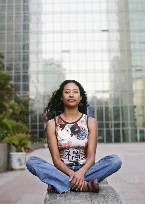 Portrait of serious mixed race woman sitting near highrise