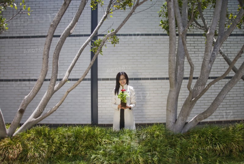 Asian woman holding flower near trees