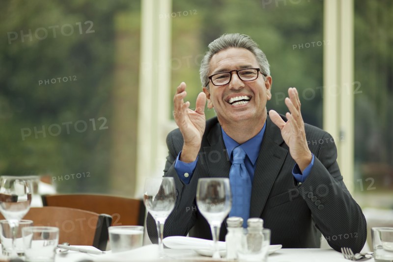 Excited Hispanic businessman sitting at table in restaurant