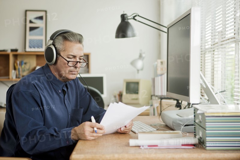 Hispanic businessman reading paperwork and listening to headphones