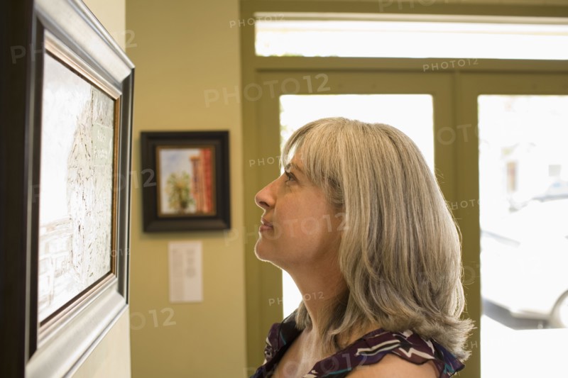 Caucasian woman admiring painting in gallery
