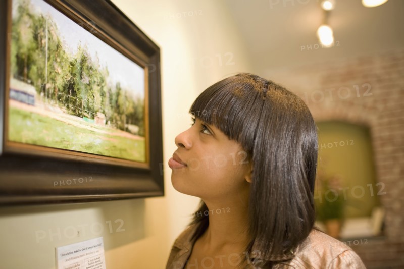 Mixed race woman admiring painting in gallery