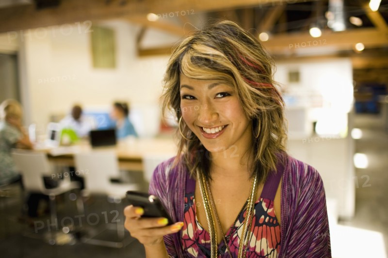 Japanese businesswoman using cell phone in communal workspace