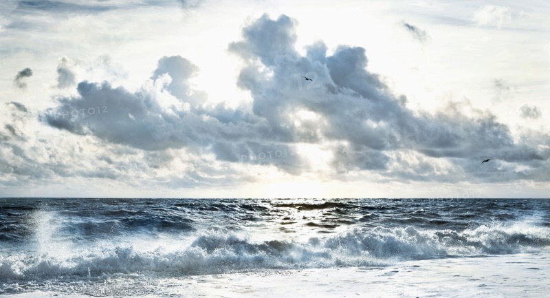 Cloudy sky over stormy waves on beach