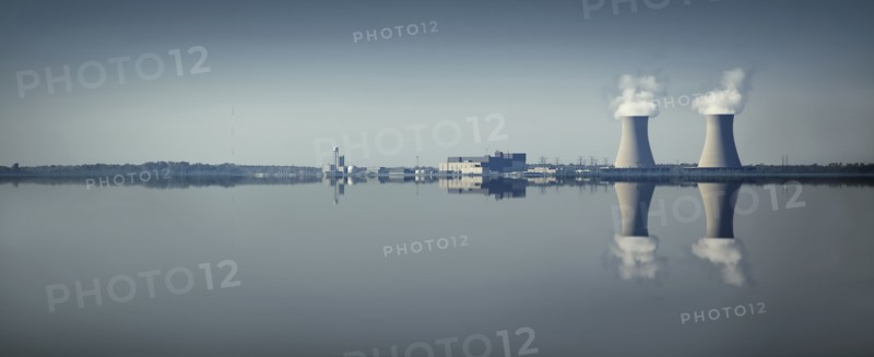 Smoke stacks and factory reflected in still lake