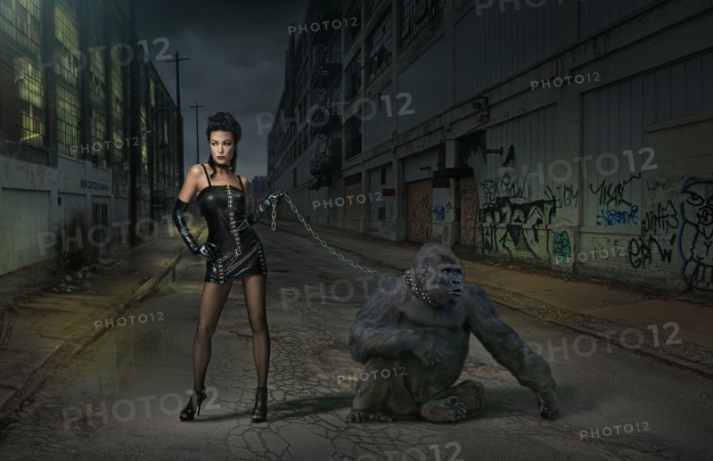 Caucasian woman with gorilla on chain on city street
