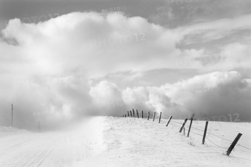 Clouds and wooden fence in snowy landscape