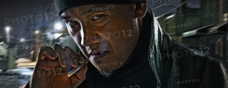 Asian man smoking on city street