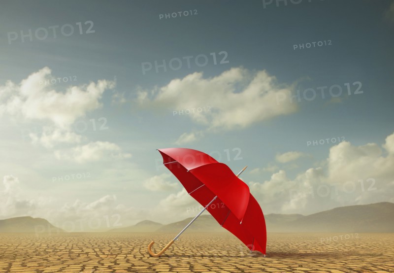 Red umbrella in desert landscape