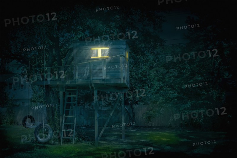 Illuminated treehouse in backyard at night