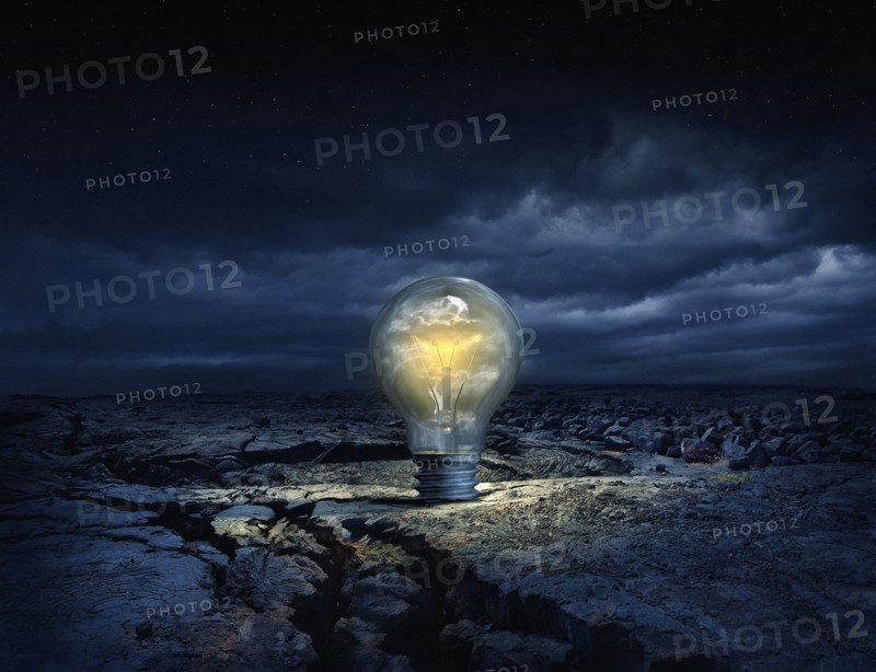 Illuminated light bulb in cracked earth