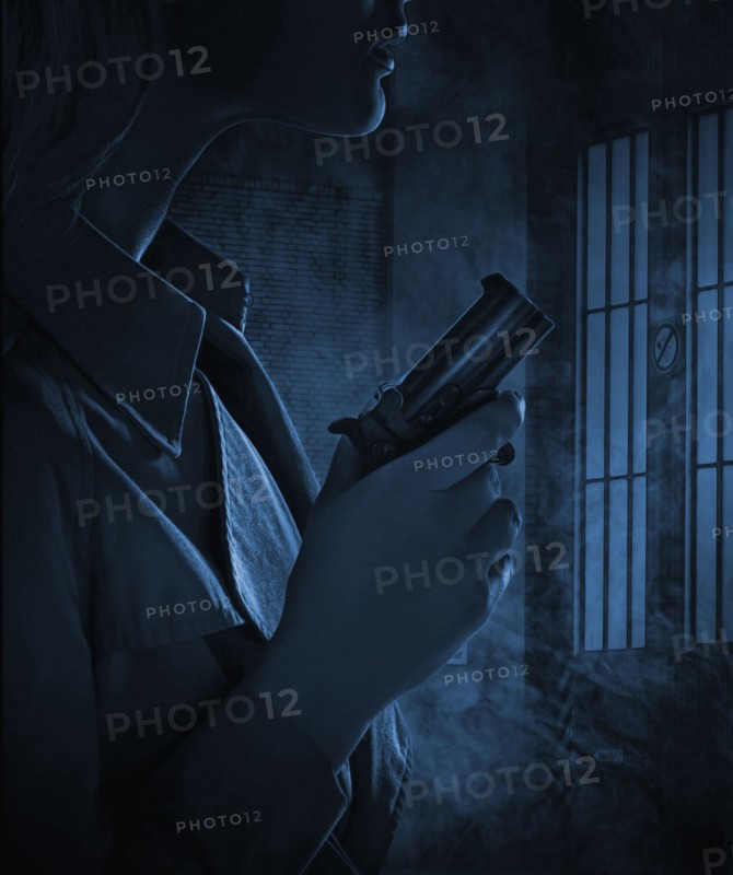 Silhouette of woman holding gun in dark room