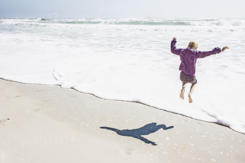 Girl playing in waves on sunny beach