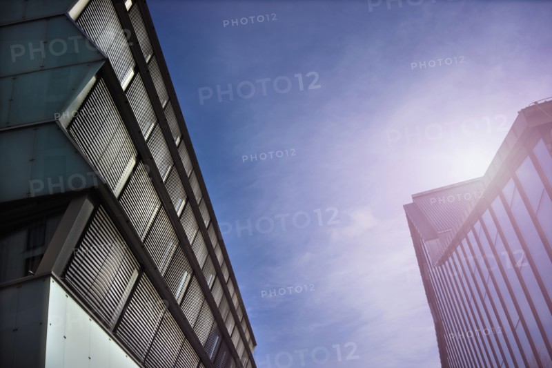 Low angle view of sunbeams over modern buildings