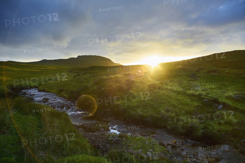 Sunrise over rural hills and stream