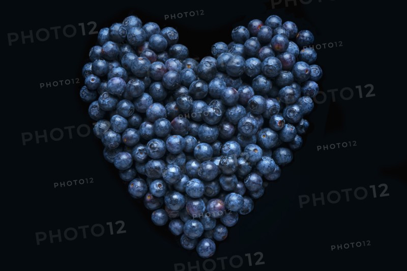 Blueberries in shape of heart on black background