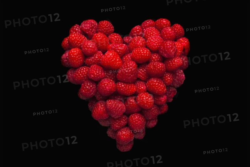 Raspberries in shape of heart on black background