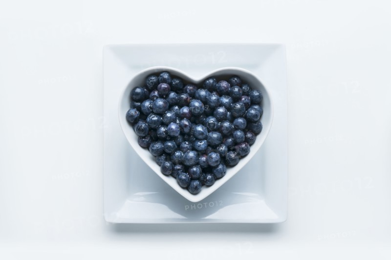Blueberries in heart-shape bowl on white background