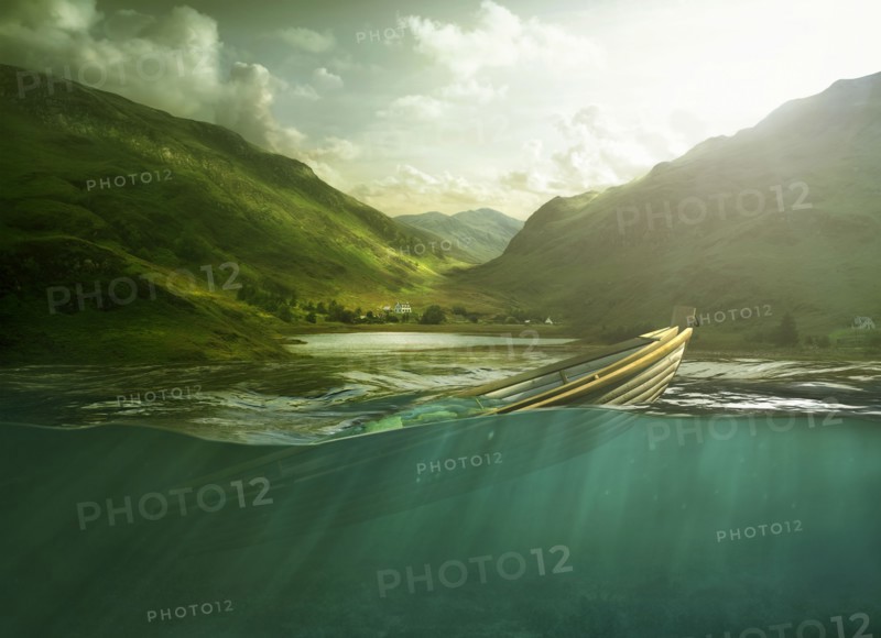 Rowboat sinking in lake near mountains