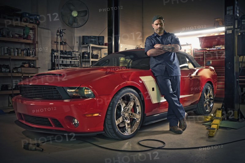 Caucasian mechanic posing on red sports car