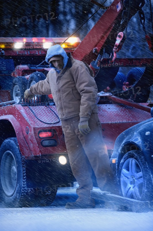 Serious Caucasian tow truck driver towing car