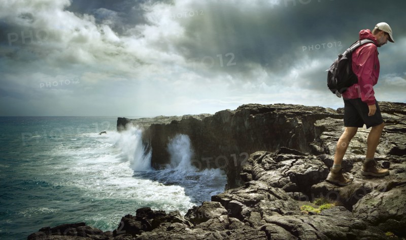 Caucasian man hiking on rocky shore
