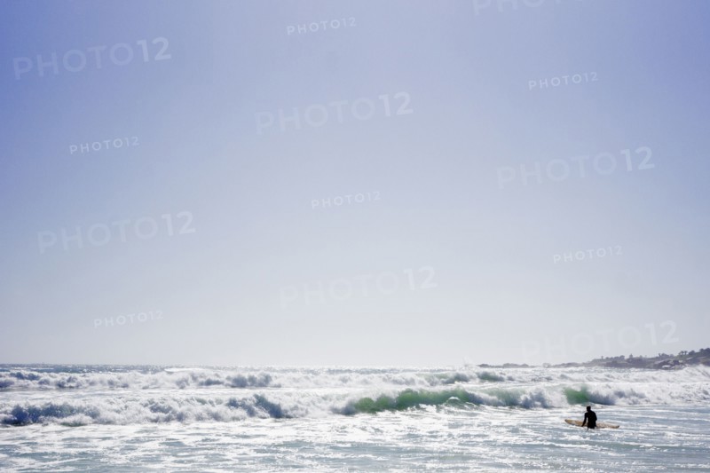 Surfer holding surfboard in ocean waves