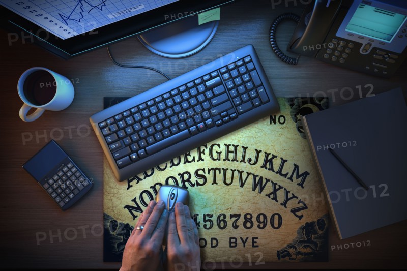 Hands using computer mouse on Ouija board