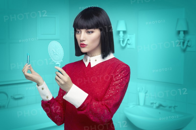 Caucasian woman in teal old-fashioned bathroom applying lipstick