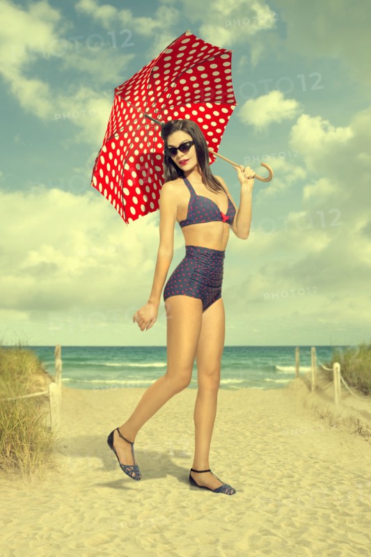 Caucasian woman holding polka-dot umbrella at beach