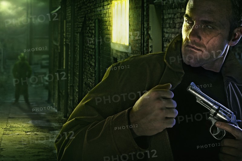 Suspicious man with scar on face holding gun in alley