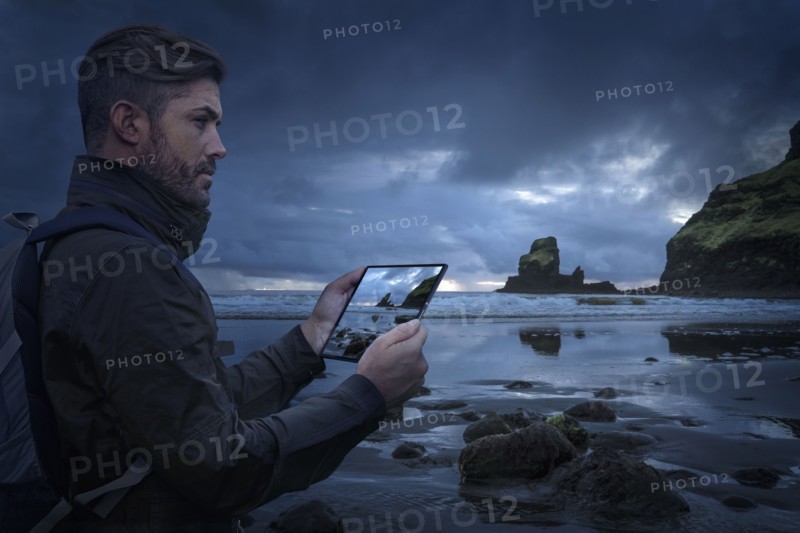 Caucasian hiker photographing beach with digital tablet at sunset