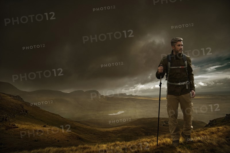 Caucasian hiker holding walking stick in cloudy landscape