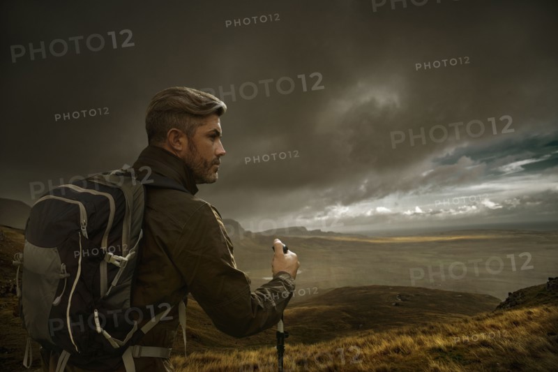 Caucasian hiker holding walking in cloudy landscape