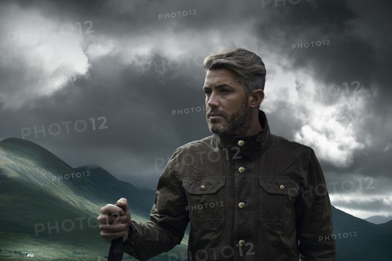 Caucasian hiker holding walking stick in cloudy landscape