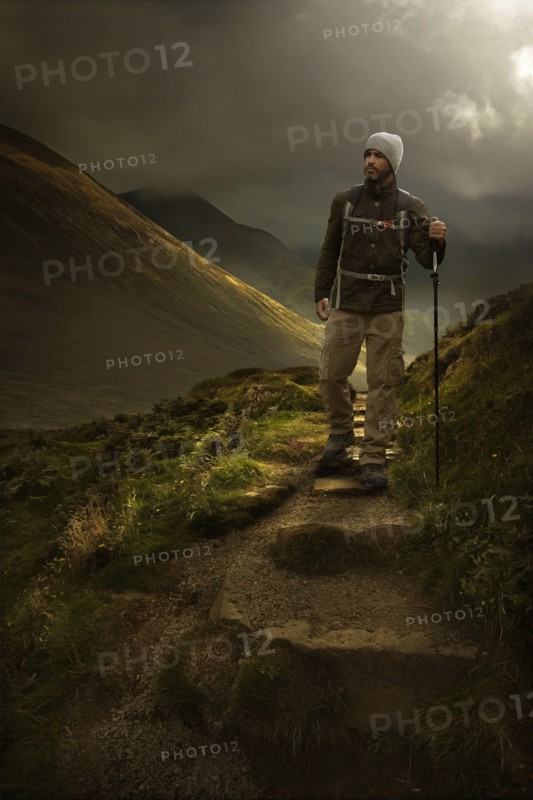 Caucasian hiker holding walking stick on mountain path